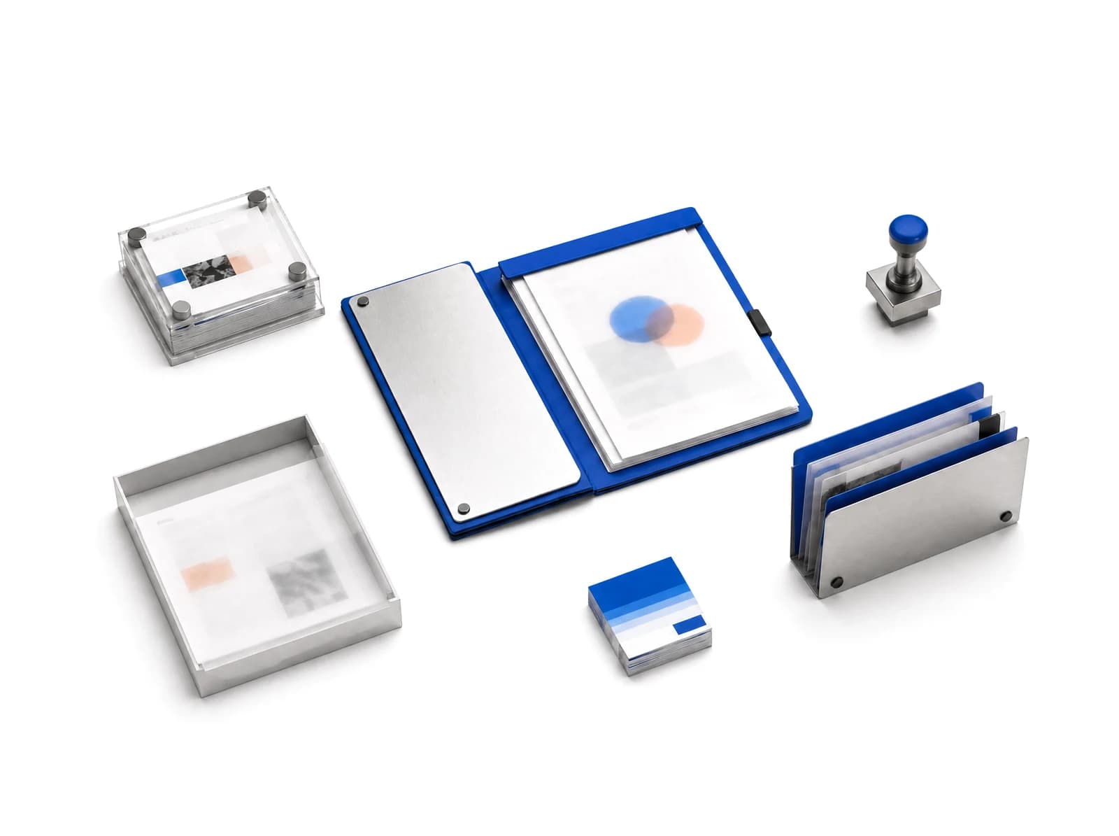 An open cobalt work folio with a stack of source cards, a tray of documents, an approval stamp, and a file holder, arranged with space between them.